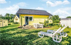 a yellow house with two lawn chairs and a table at 2 Bedroom Amazing Home In Dabki in Dąbki
