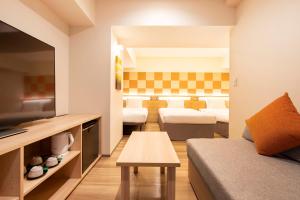 a room with two beds and a couch and a tv at karaksa hotel TOKYO STATION in Tokyo