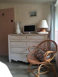 Habitación con silla y tocador con TV. en Le gîte de Camille, en Saint-Hilaire-de-Talmont