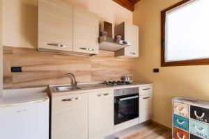 Una pequeña cocina con gabinetes de madera y un fregadero. en Casa Maralesi By BarbarHouse, en Veglie