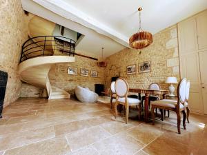 Un comedor con escalera y mesa y sillas. en Clos Saint-Priscus - Gîte de Charme - Les Bastides d'Edouard en Bourgogne, en Saint-Bris-le-Vineux