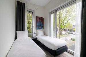 two beds in a room with a window at YAYS Amsterdam Prince Island by Numa in Amsterdam