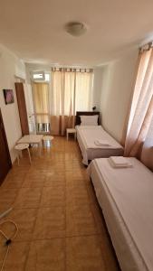 a room with two beds and a table and windows at S Apartment in Tsarevo
