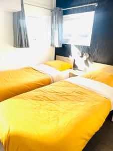two beds in a hotel room with yellow sheets at Cottage Premium, camping 5* avec parc aquatique in Hudimesnil