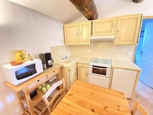 a kitchen with white cabinets and a microwave and a table at LA CONFISERIE in Saint-Sauveur-de-Cruzières