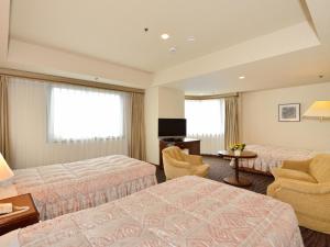 a hotel room with two beds and a desk at Grand Hotel Hamamatsu in Hamamatsu