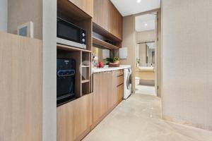 a kitchen with wooden cabinets and a sink at Lumina by Kozystay - Cilandak in Jakarta