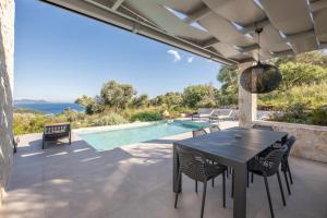 a patio with a table and chairs and a swimming pool at Mesogi Villas, brand new modern, stylish villas, private pool, seaviews in Meganisi