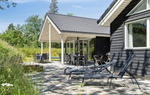 a patio with chairs and tables outside of a house at Stunning Home In Væggerløse With Sauna in Marielyst +27 photos