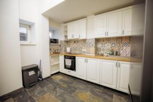 a kitchen with white cabinets and a tile wall at Miniszteri House in Băile Tuşnad