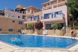 a person swimming in a swimming pool next to a building at Tala Hills Sea View Apartment, Tala Village, Paphos in Tala