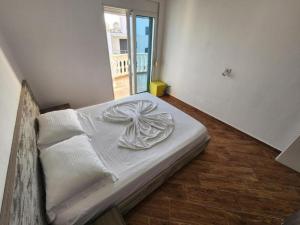 a white bed in a room with a window at Blue Sea View Apartment in Sarandë