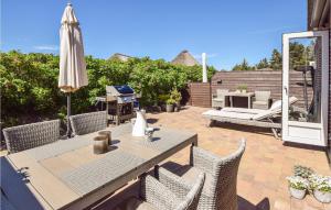 a patio with a table and chairs and an umbrella at Holiday Home Horns Bjerge Vi in Blåvand +18 photos