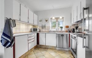 a kitchen with white cabinets and stainless steel appliances at Holiday Home Horns Bjerge Vi in Blåvand