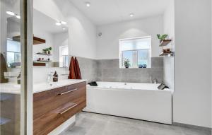 a white bathroom with a tub and a sink at Holiday Home Horns Bjerge Vi in Blåvand