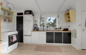 a kitchen with white cabinets and a white refrigerator at Cozy Home In Nexø With House Sea View in Neksø