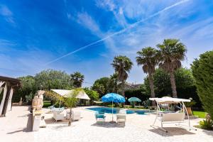 a pool with chairs and umbrellas on a patio at Villa Vinne Cirase in Castiglione dʼOtranto