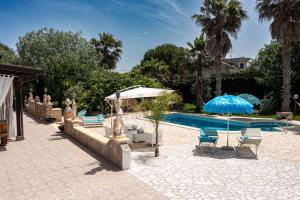 a swimming pool with two chairs and an umbrella at Villa Vinne Cirase in Castiglione dʼOtranto