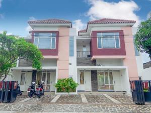 two motorcycles parked in front of a pink building at Omah Ireda Guesthouse in Yogyakarta