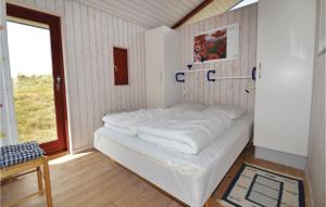 a white bed in a room with a window at Holiday Home Kåverknoldene in Fanø +4 photos