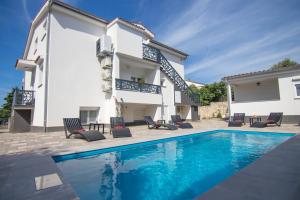 a villa with a swimming pool and a house at Apartments Flowers - Heated Pool Near Beach in Krk