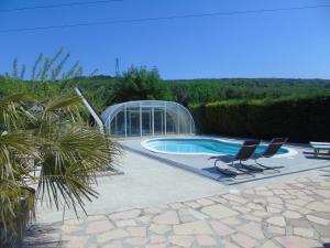 a swimming pool with two chairs and a glass house at Aux Lauriers d'Adhémar in La Garde-Adhémar