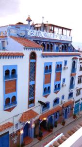 a blue and white building with a clock on it at Résidence Hoteliére Chez Aziz in Chefchaouen