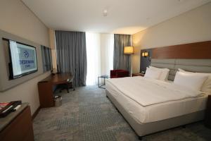 a hotel room with a bed and a television at Dedeman Cizre Hotel in Jesıret ibn Omar