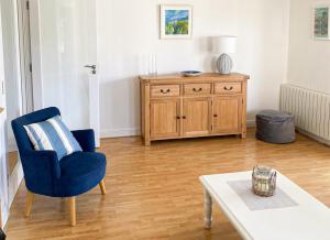 a living room with a blue chair and a table at Moore Bay Holiday Homes No 18A by Trident Holiday Homes in Kilkee