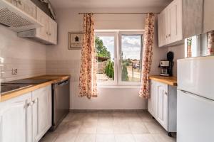 a kitchen with white cabinets and a window at Domek Masuria in Orzysz