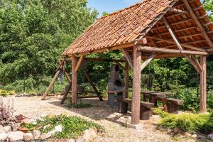 a wooden gazebo with a bench and a swing at Domek Masuria in Orzysz