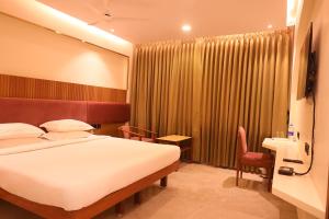 a hotel room with a bed and a desk at Hotel Surguru in Puducherry