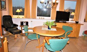 ein Esszimmer mit Tisch und Stühlen und einem Fernseher in der Unterkunft Haus Halligblick, Ferienwohnungen am Wattenmeer, Whg Gröde in Dagebüll