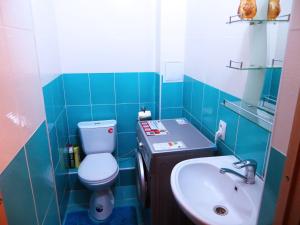W wyłożonej niebieskimi kafelkami łazience znajduje się toaleta i umywalka. w obiekcie Apartment Kievskaya 114/2 w mieście Biszkek