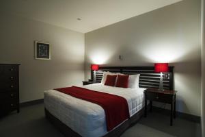 a hotel room with a large bed with red lamps at Emerald Hotel in Gisborne