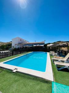 a large swimming pool with lounge chairs and umbrellas at CASA RURAL PRIVADA El ASIENTO LOS GEMELOS in Pruna