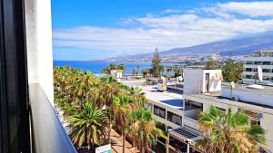 a view of the ocean from a building with palm trees at Parque Santiago II - Air Conditioning - Ocean View - 350mt from the beach in Playa de las Americas