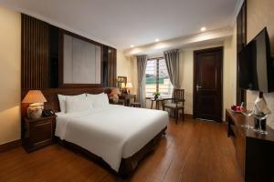 een slaapkamer met een groot wit bed en een bureau bij The West Hotel & Spa in Hanoi