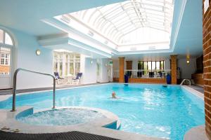 a child swimming in a pool with a skylight at Tylney Hall Hotel in Hook
