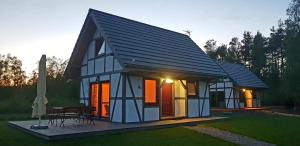 a small house with a black roof and a table at Domek Pogodny Rowy Szachulcowa 4a in Rowy