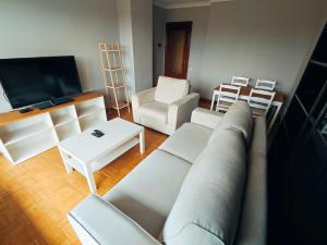 a living room with white furniture and a flat screen tv at La atalaya de Coto in Salinas