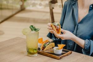 阿尔布费拉Aqua Pedra Dos Bicos Design Beach Hotel - Adults Friendly的一位女士在桌上吃三明治和饮料
