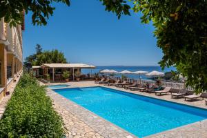a pool with chairs and umbrellas next to a building at Apart Hotel Alex in Himare