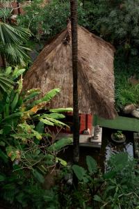 aikiikiikiiki house with a grass roof in a garden at Fourteen Roses Boutique Hotel, Kuta in Legian
