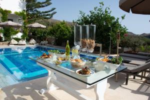 a table with food on it next to a swimming pool at Infinity Wellness Boutique Hotel in Afráta
