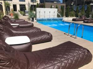 a row of brown chairs next to a swimming pool at Malūno vilos in Palanga