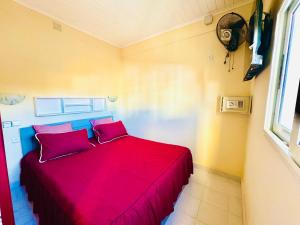 a bedroom with a red bed with two red pillows at Hôtel - Appartement " LES FLOTS BLEU " in Antananarivo