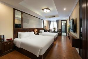 a hotel room with two beds and a table at The West Hotel & Spa in Hanoi