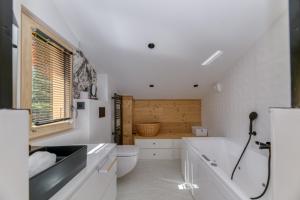 a bathroom with a tub and a toilet and a sink at Homency - Chalet La Pavicha in L'Alpe-d'Huez