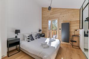 a bedroom with a white bed and a wooden wall at Homency - Chalet La Pavicha in L'Alpe-d'Huez